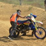 man in orange and blue shirt riding blue and black motocross dirt bike